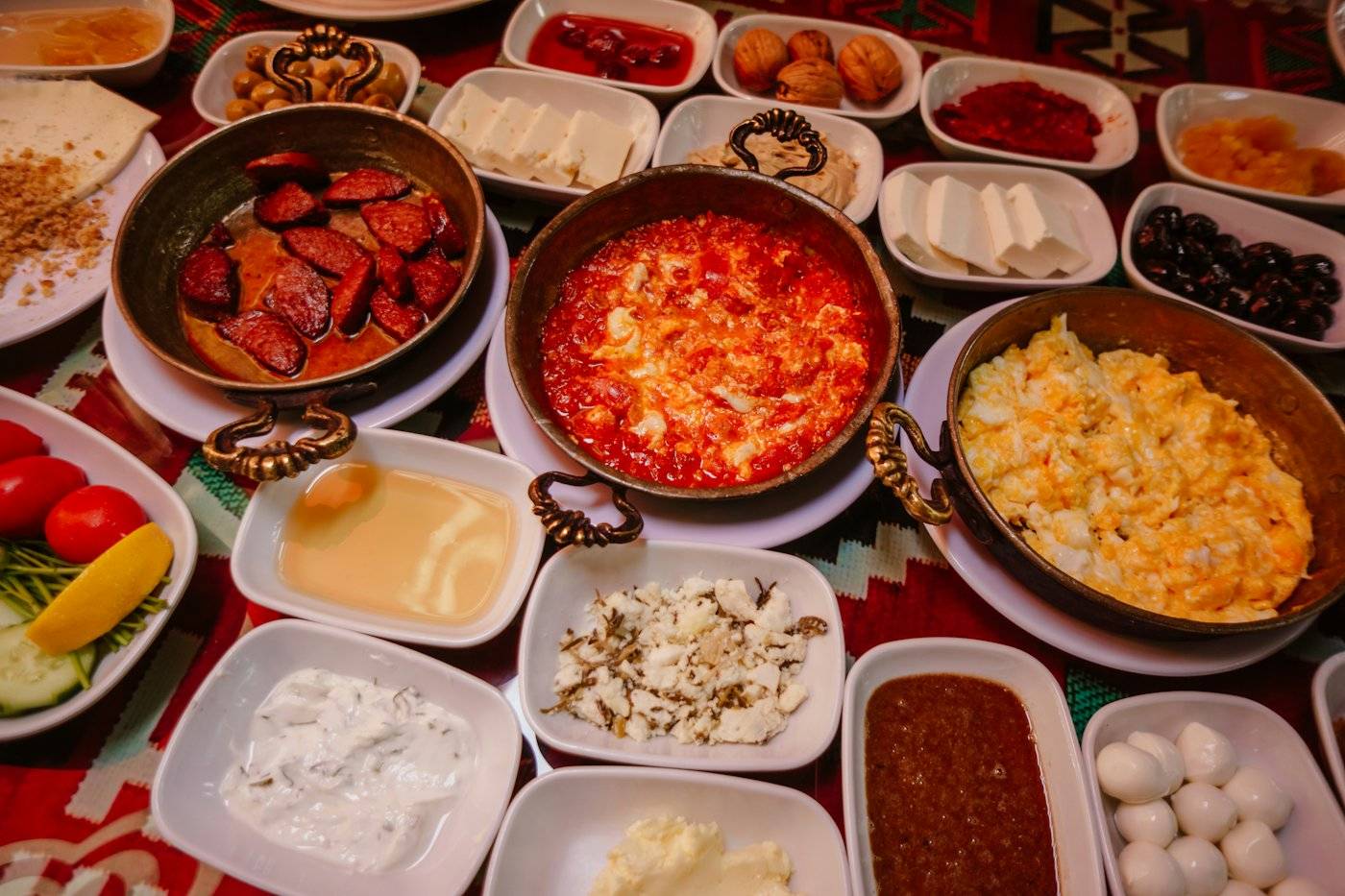 Peynir, zeytin, reçel, menemen ve çay bardaklarıyla kurulmuş kahvaltı sofrası